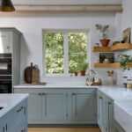 Light wood flooring grounding a blue Shaker kitchen design