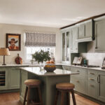 Sage green kitchen with bespoke kitchen island, marbled quartz worktop and rustic wooden stools.