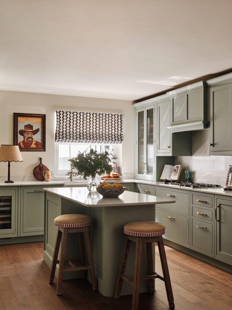 Sage green kitchen with bespoke kitchen island, marbled quartz worktop and rustic wooden stools.