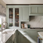 Light filled kitchen with patterned Roman blind, marble splashback and fluted glass cabinet