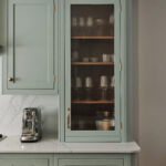 Fluted reeded glass cabinet adds texture and elegance while softly obscuring storage in this sage green kitchen