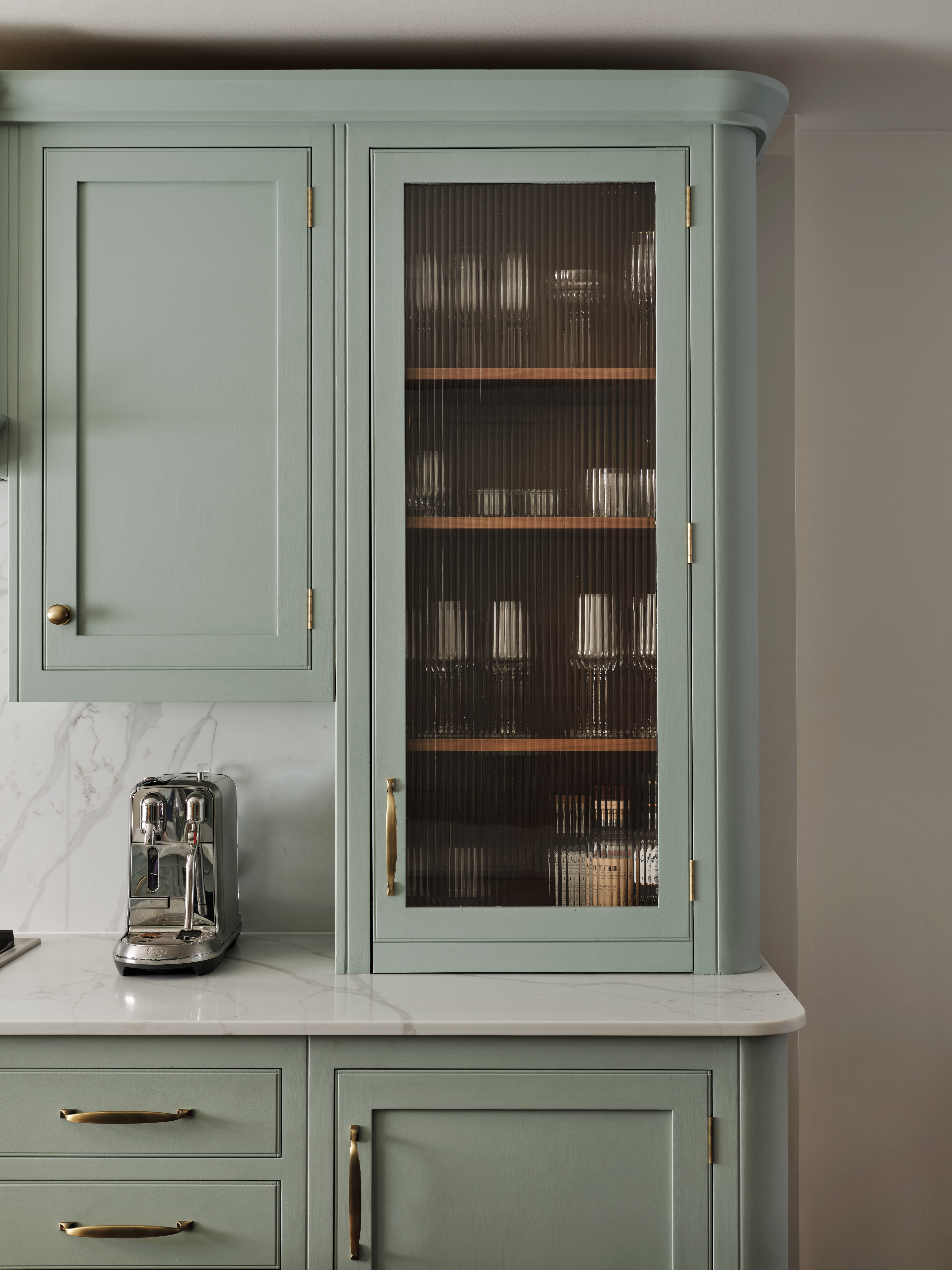 Fluted reeded glass cabinet adds texture and elegance while softly obscuring storage in this sage green kitchen