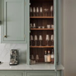 Hidden bar cabinet with fluted glass doors conceals glassware and drinks, blending bespoke storage into the luxury kitchen cabinetry