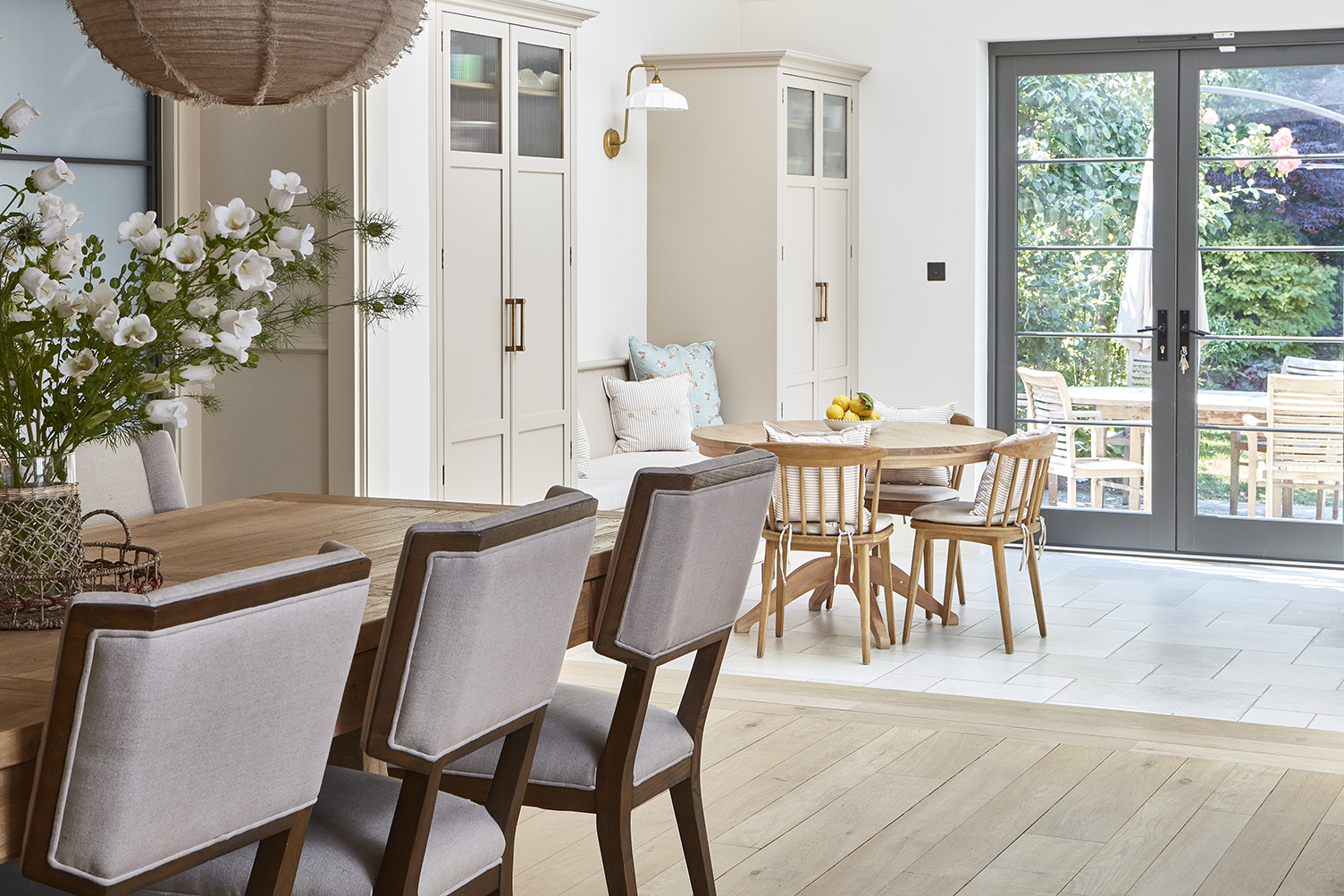Bright open plan kitchen diner with banquette seating and natural textures to compliment the feminine pink kitchen colour palette