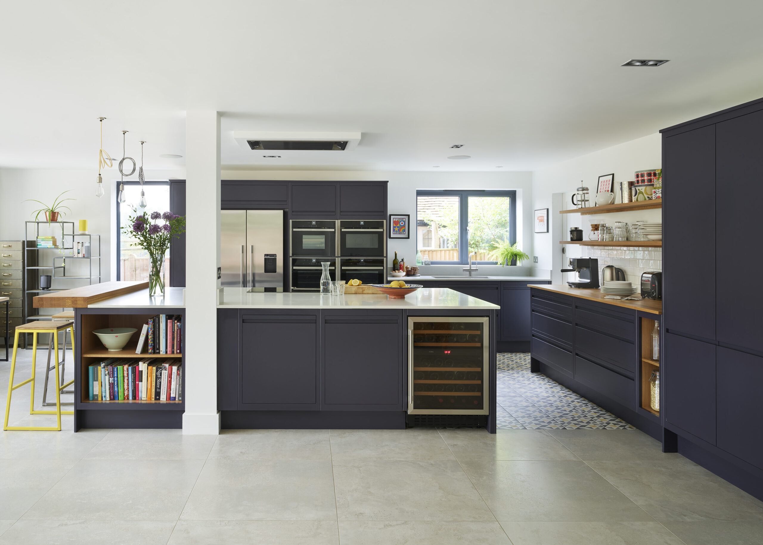 Luxury kitchen featuring navy cabinetry, ceiling extractor fan and island hob with clean, minimalist lines.