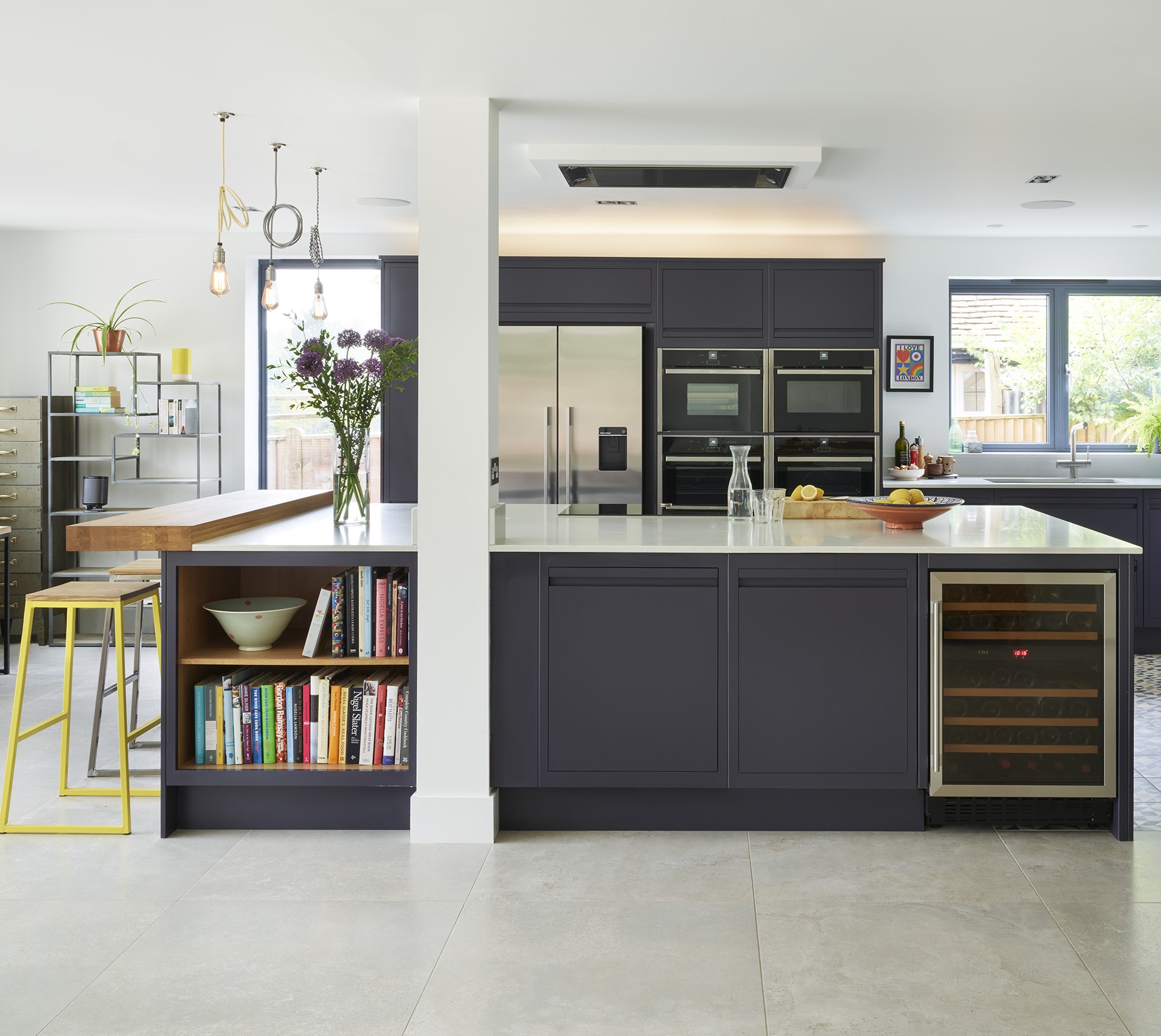 Modern navy kitchen island with off white quartz worktop, stained oak breakfast bar and integrated storage drawers.