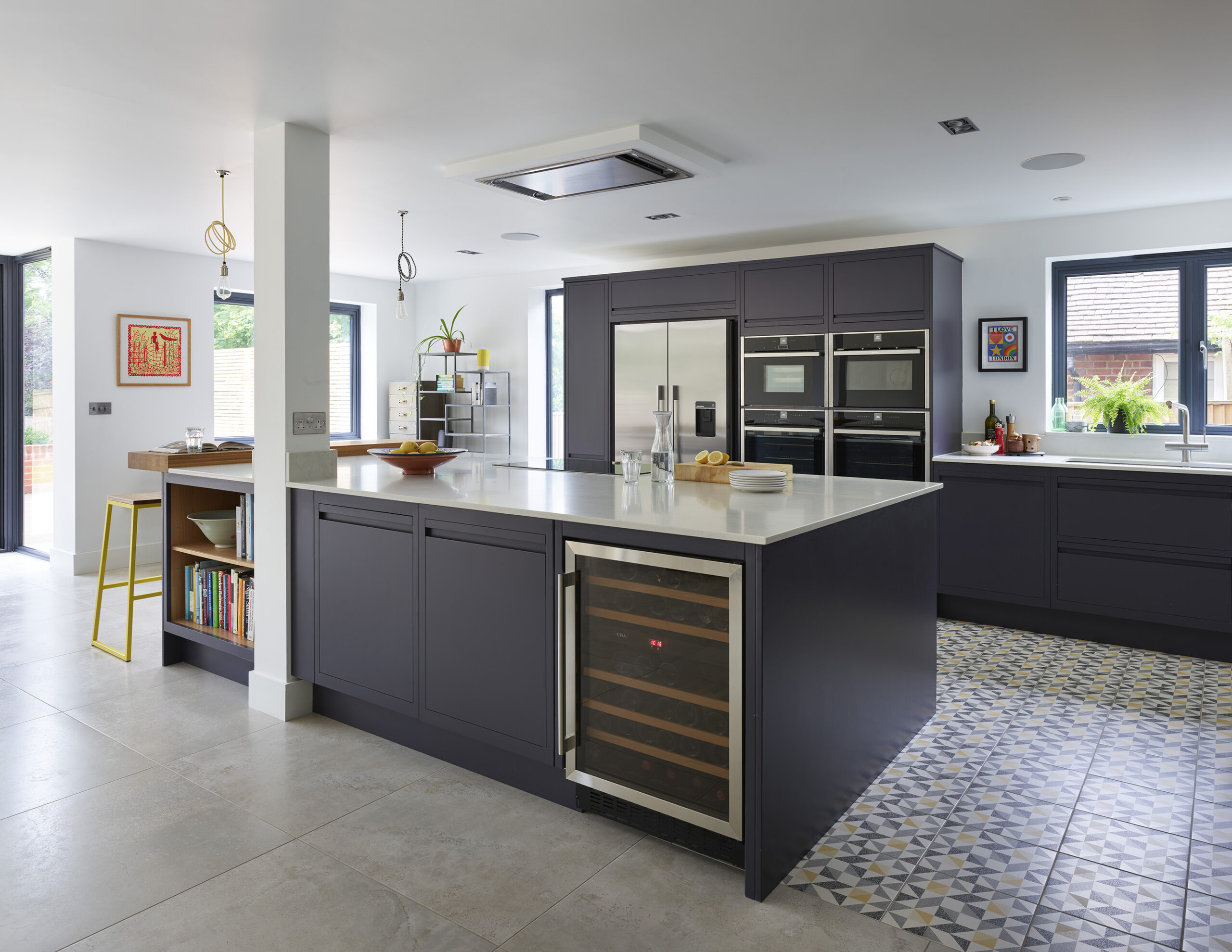 Bespoke navy kitchen island with wine fridge, recipe book shelving and oak worktop seating area.