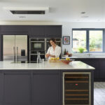 Luxury handleless kitchen in navy with industrial lighting, open shelving and integrated appliances.
