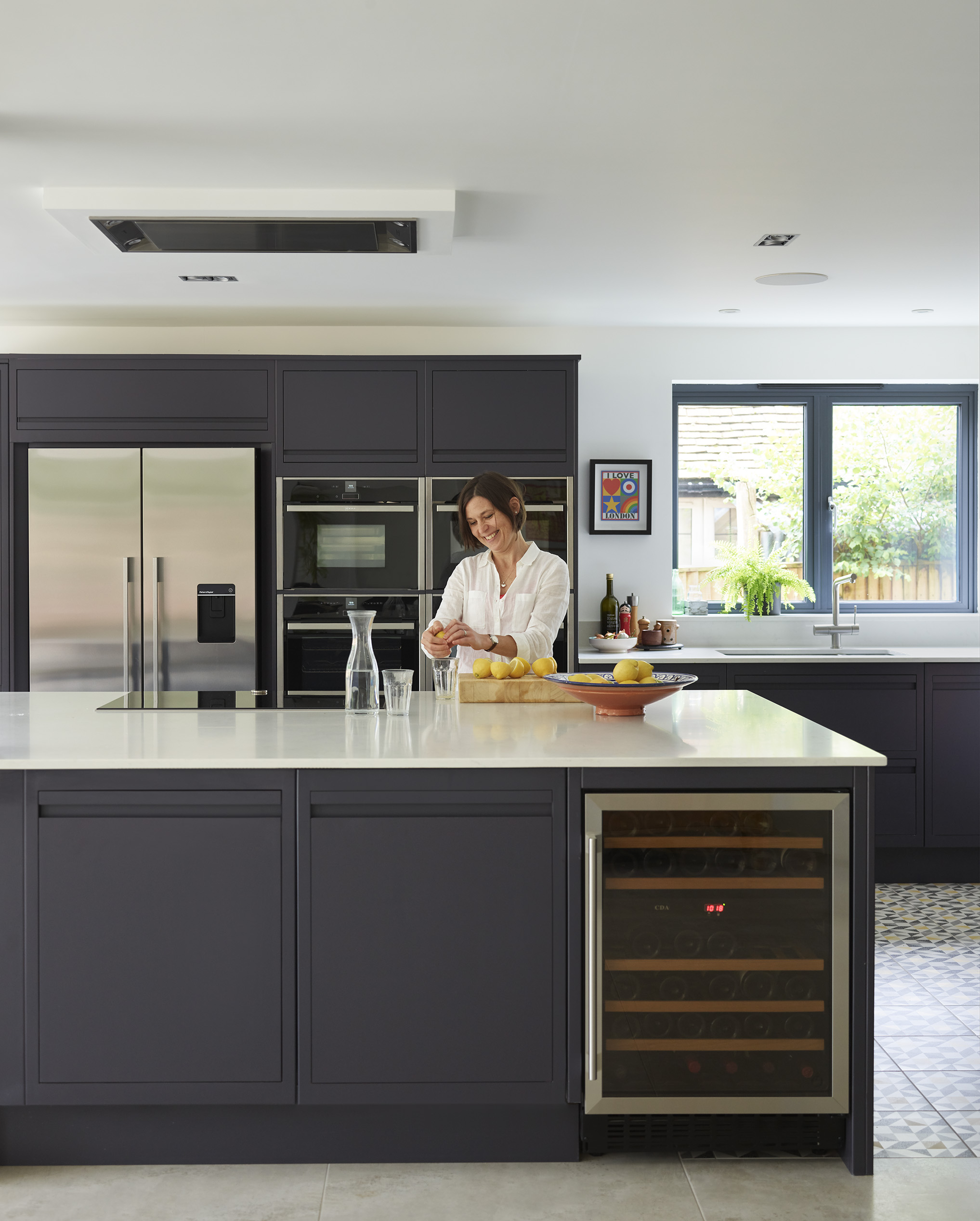 Luxury handleless kitchen in navy with industrial lighting, open shelving and integrated appliances.