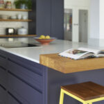 Handleless navy kitchen design with stained oak worktops adding warmth and contrast to modern cabinetry.
