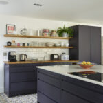 Navy kitchen with white quartz surfaces, open shelving and natural light from full length windows.