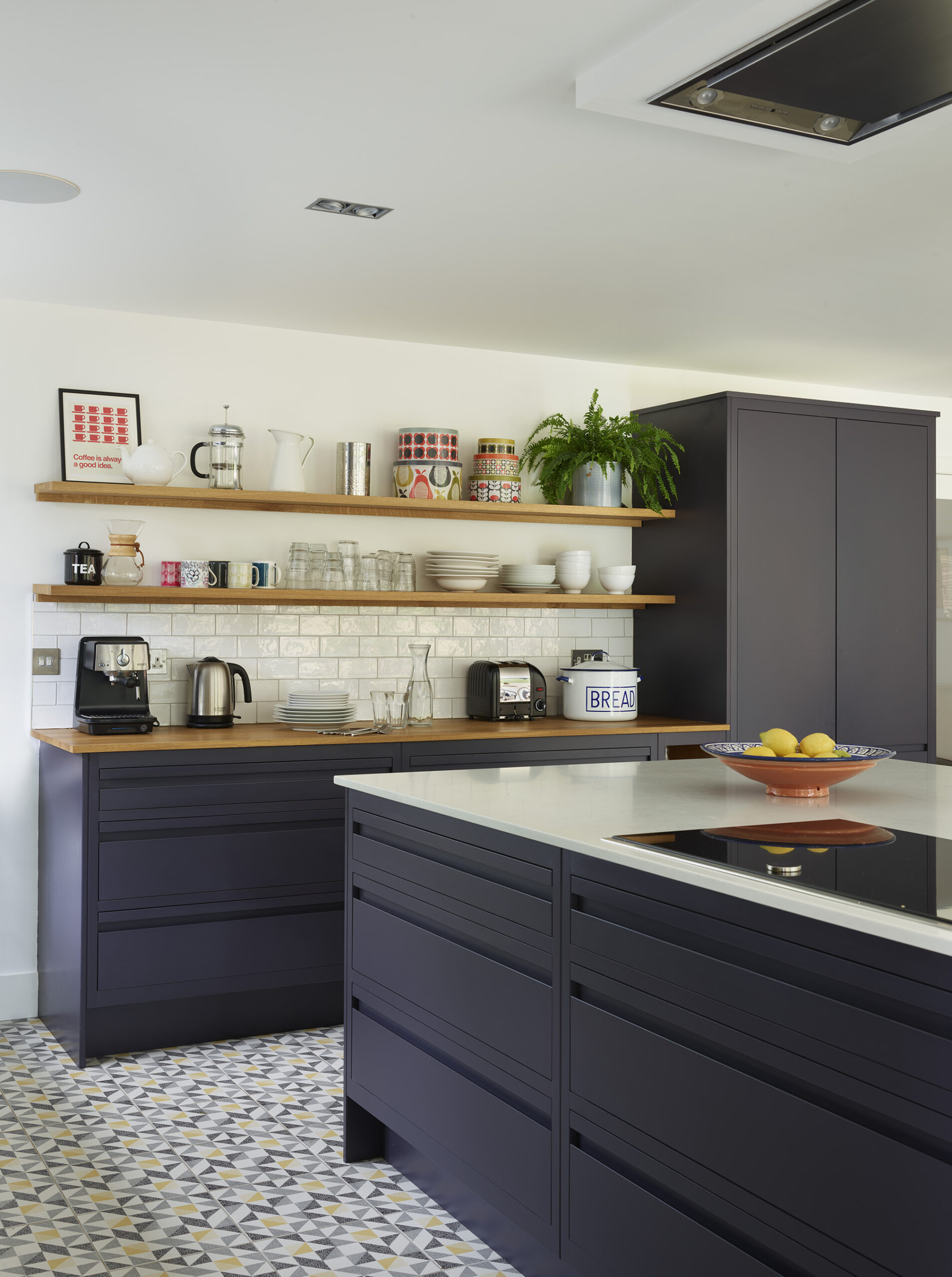 Navy kitchen with white quartz surfaces, open shelving and natural light from full length windows.