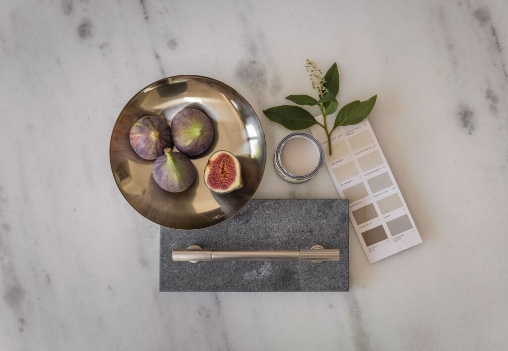 Physical moodboard with paint swatches, kitchen hardware and fruit for designing a bespoke kitchen