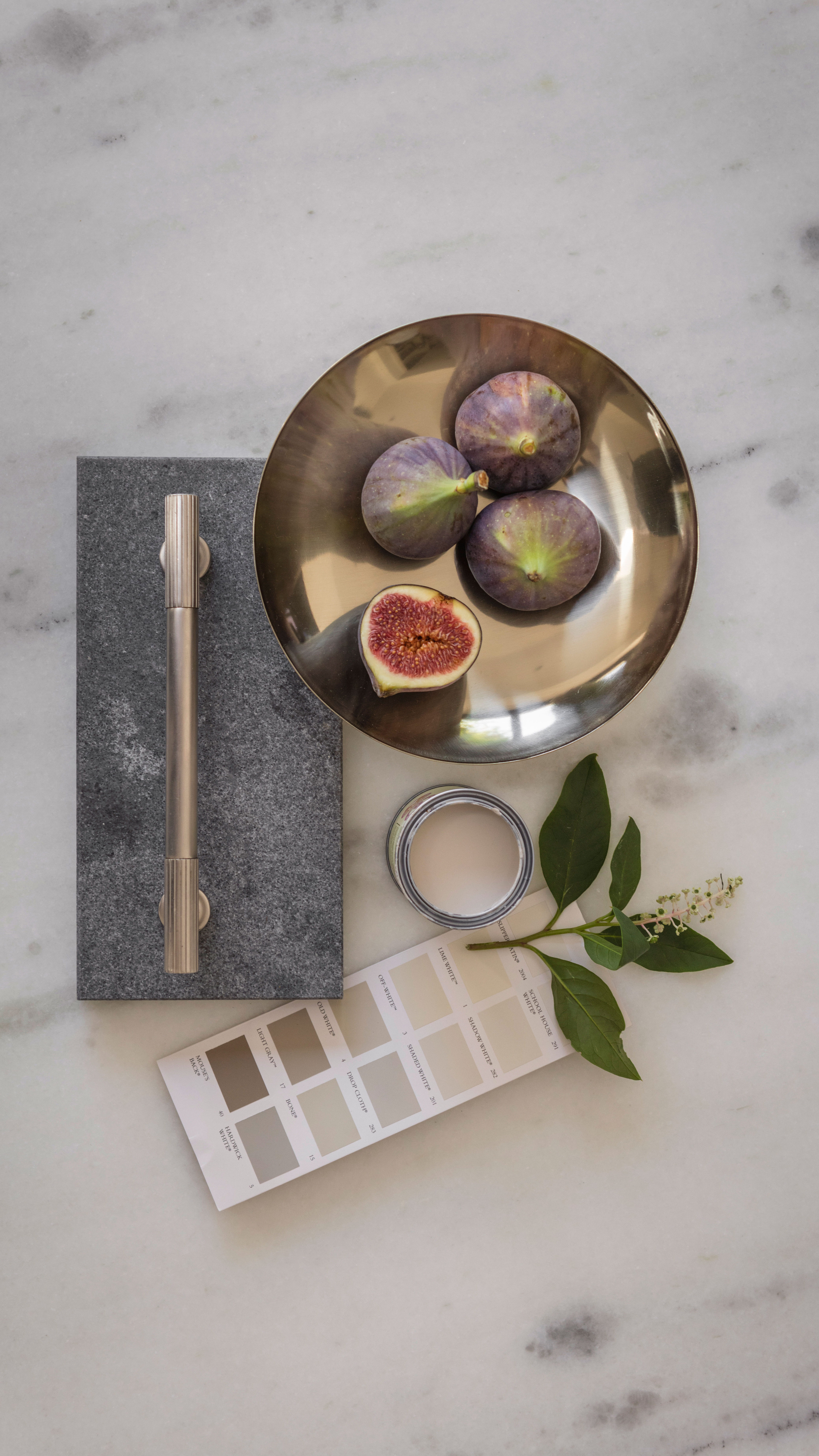 Physical moodboard with paint swatches, kitchen hardware and fruit for designing a bespoke kitchen