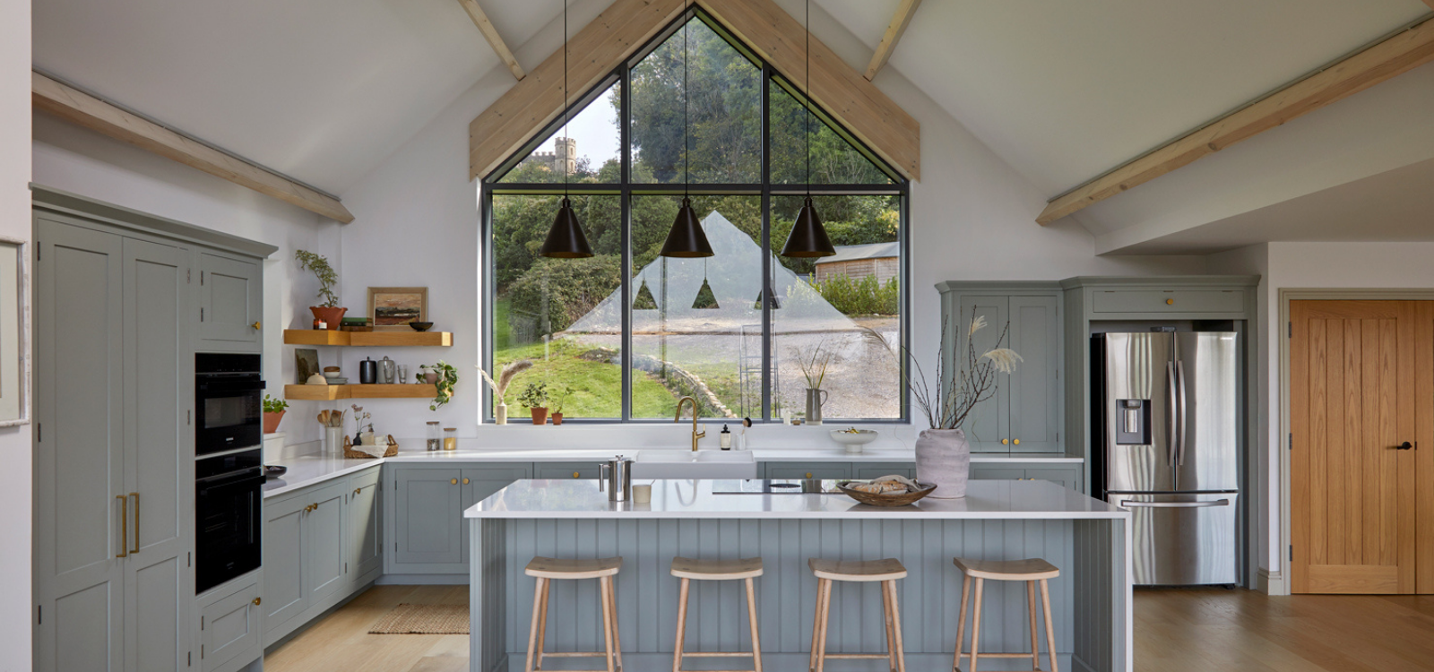 Light blue Shaker kitchen island with white quartz worktop and integrated seating.