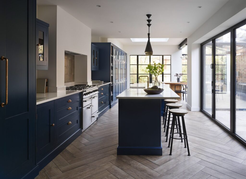 Navy blue kitchen diner with bifold doors and herringbone floor