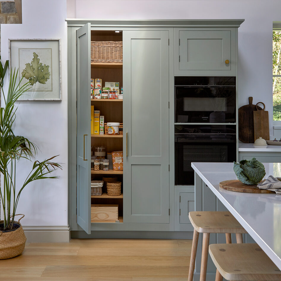 Tall pantry cabinets offering bespoke storage in a blue Shaker kitchen