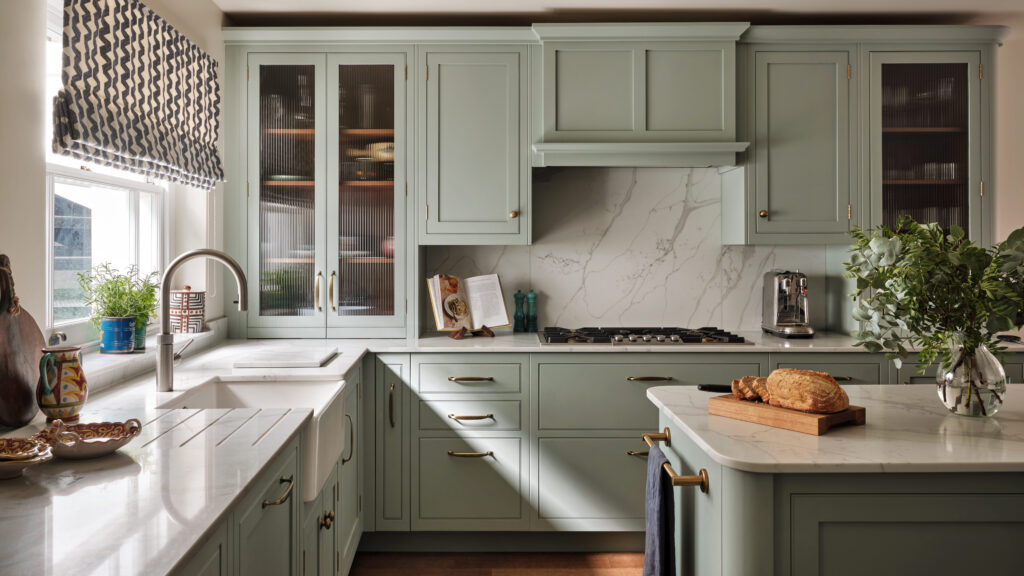 Sage green kitchen with island and glass fronted storage