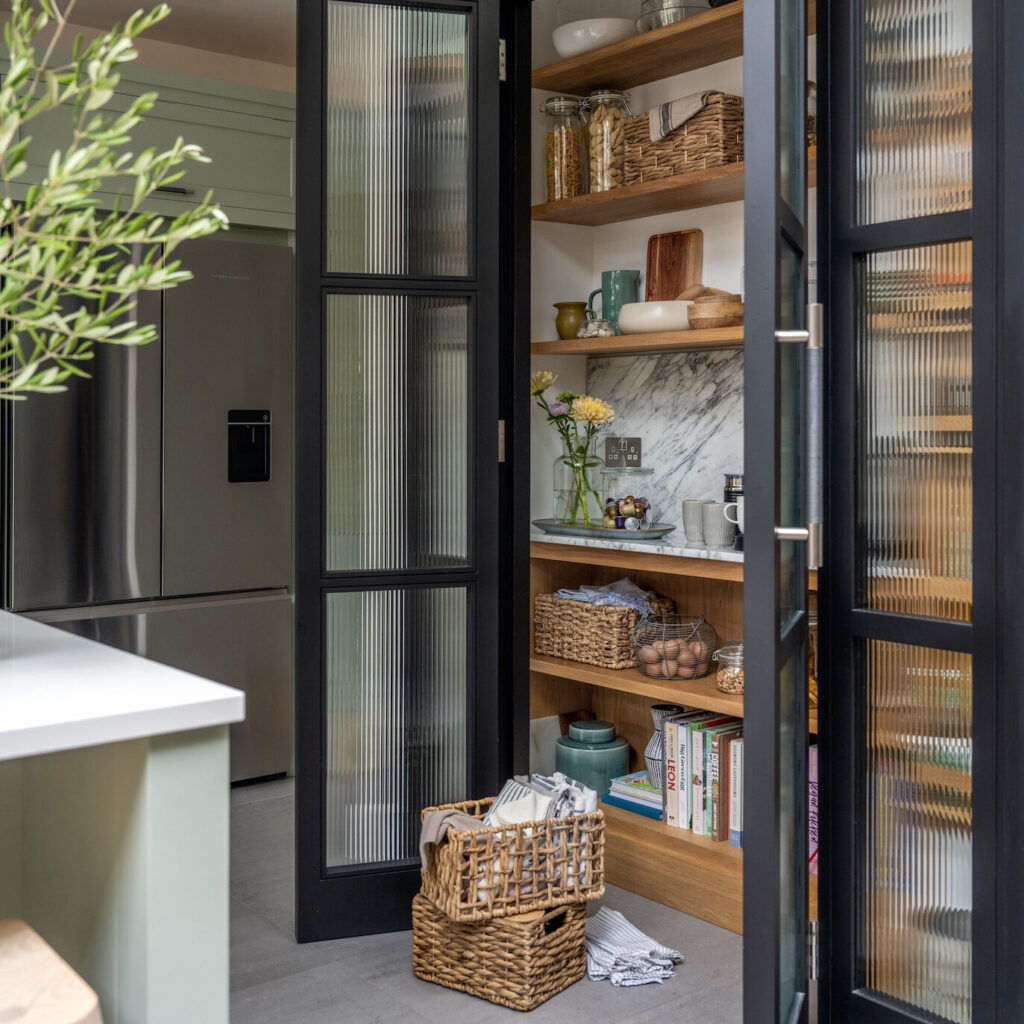 Kitchen pantry with reeded glass doors open to show organised shelving and basket storage