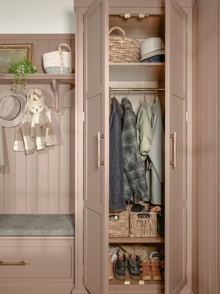 Pink boot room with tall cupboards, bench seating, coat cooks and shelving
