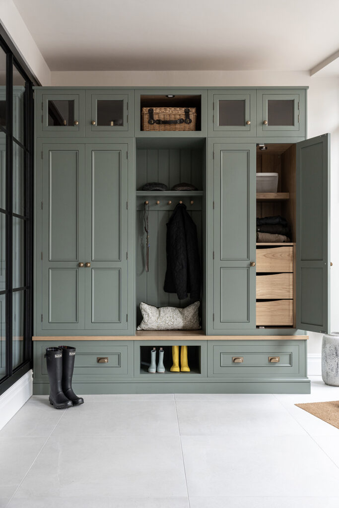 Green boot room with hidden drawers and vertical storage with bench seating