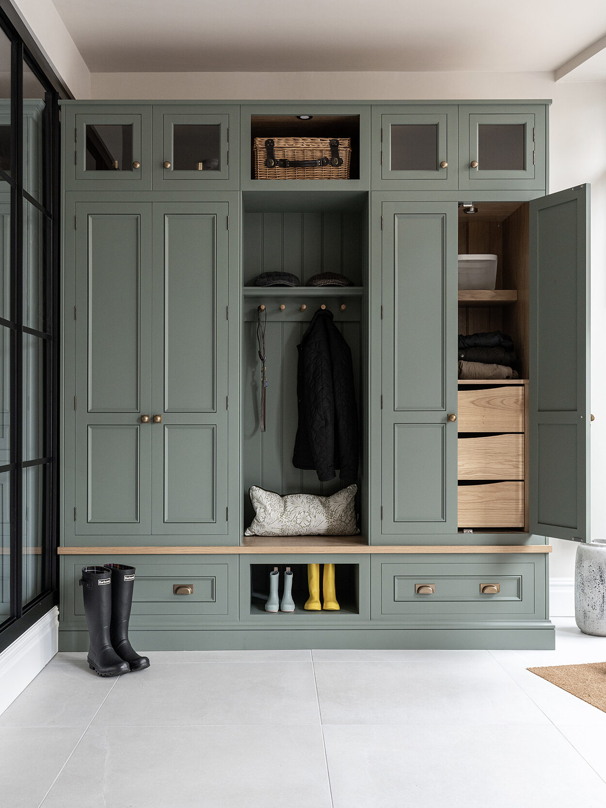 Green boot room with hidden drawers and vertical storage with bench seating