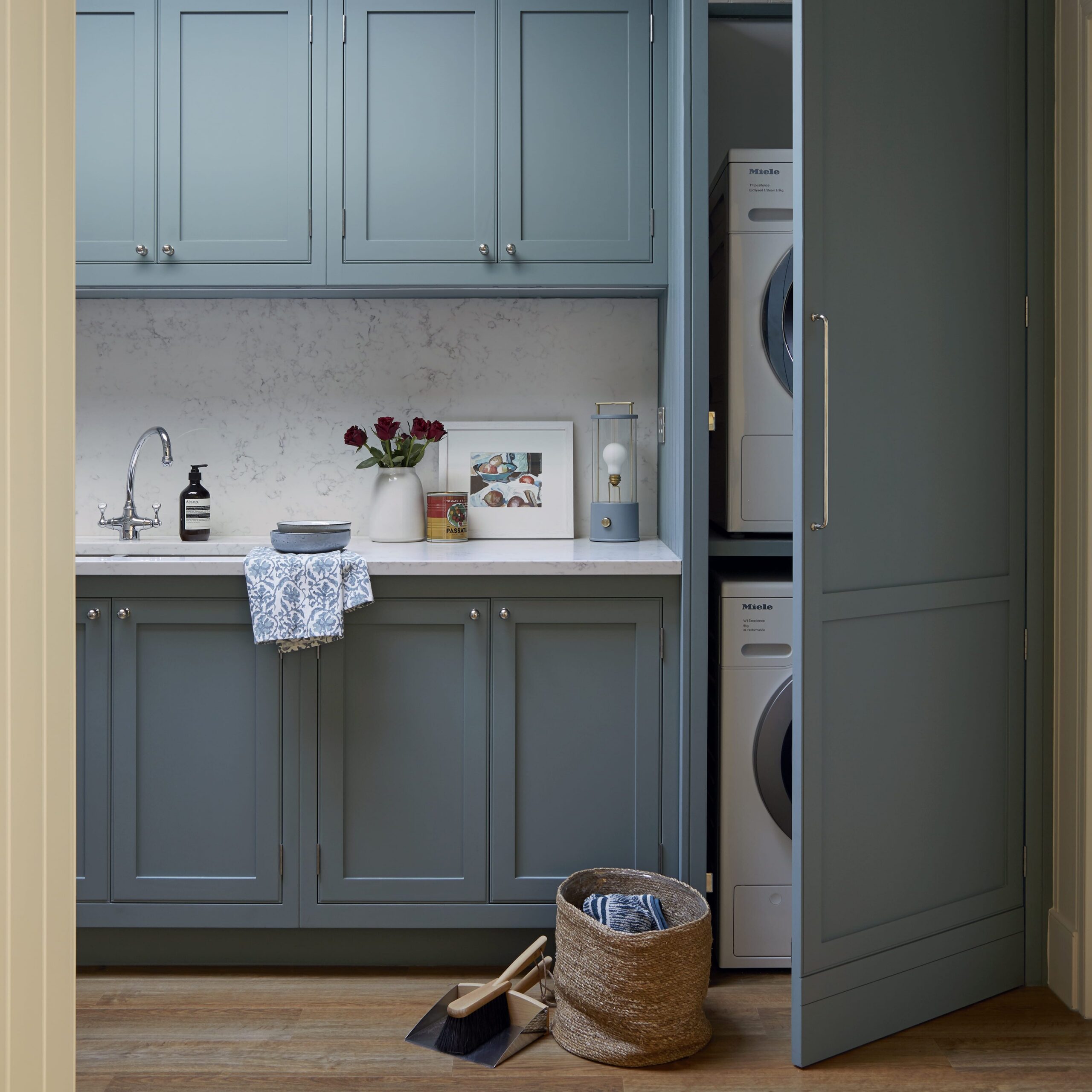 Blue utility room with hidden washer and dryer and styled worktops with sink and cabinetry space