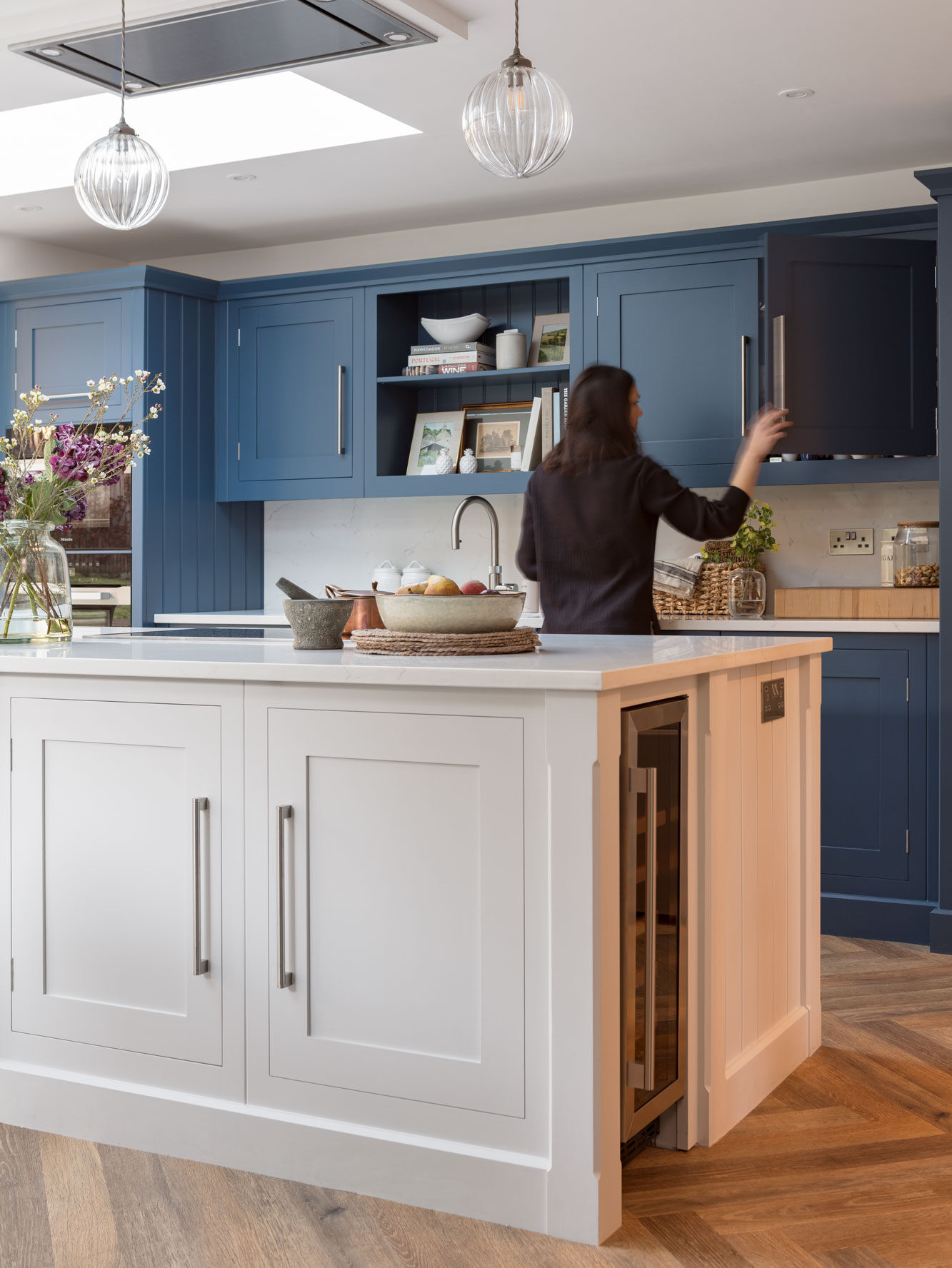 White kitchen island in a navy blue kitchen with integrated wine fridge and plug sockets