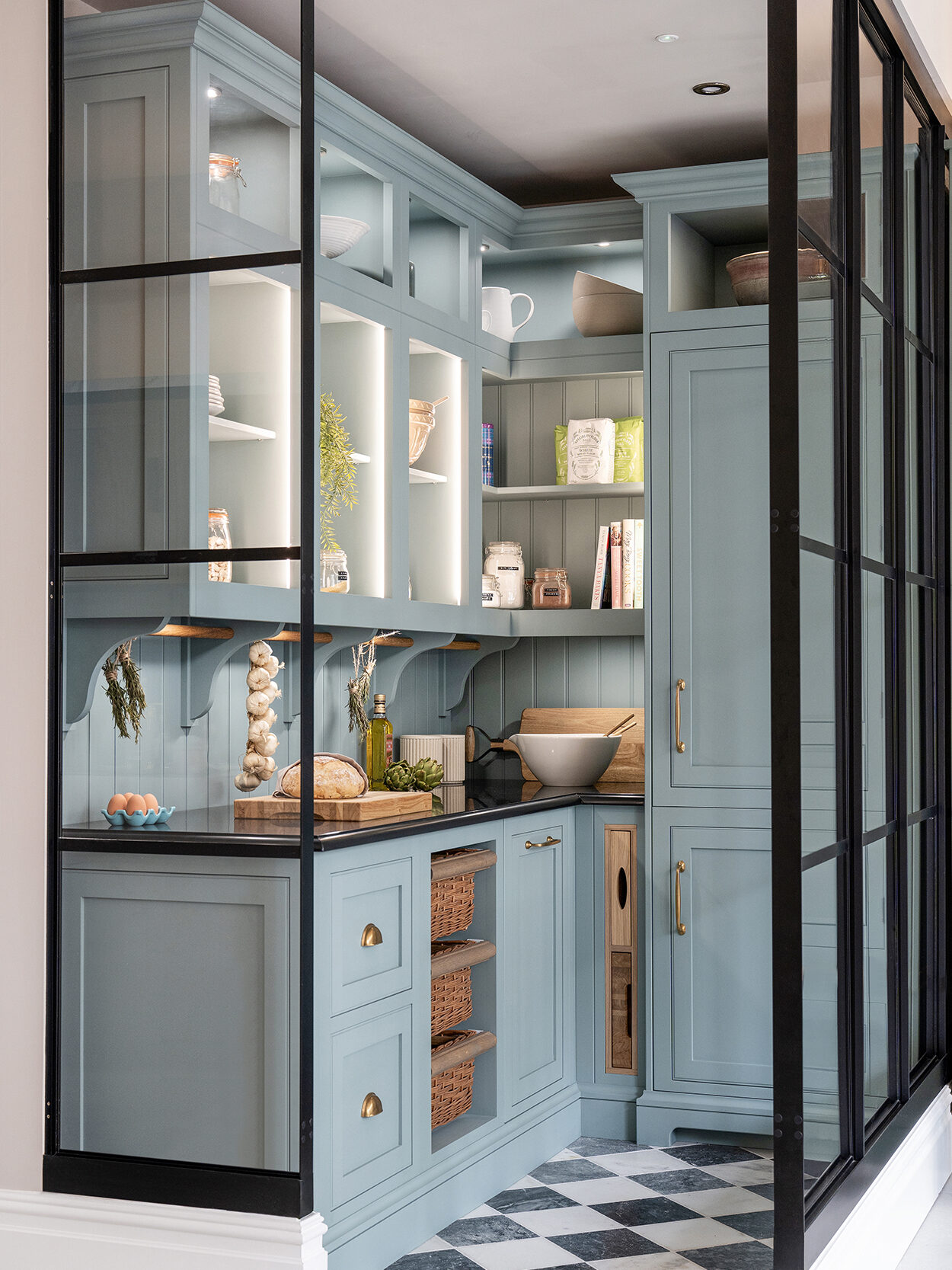 Blue walk in pantry with basket drawers, layered lighting and worktop preparation space for modern living