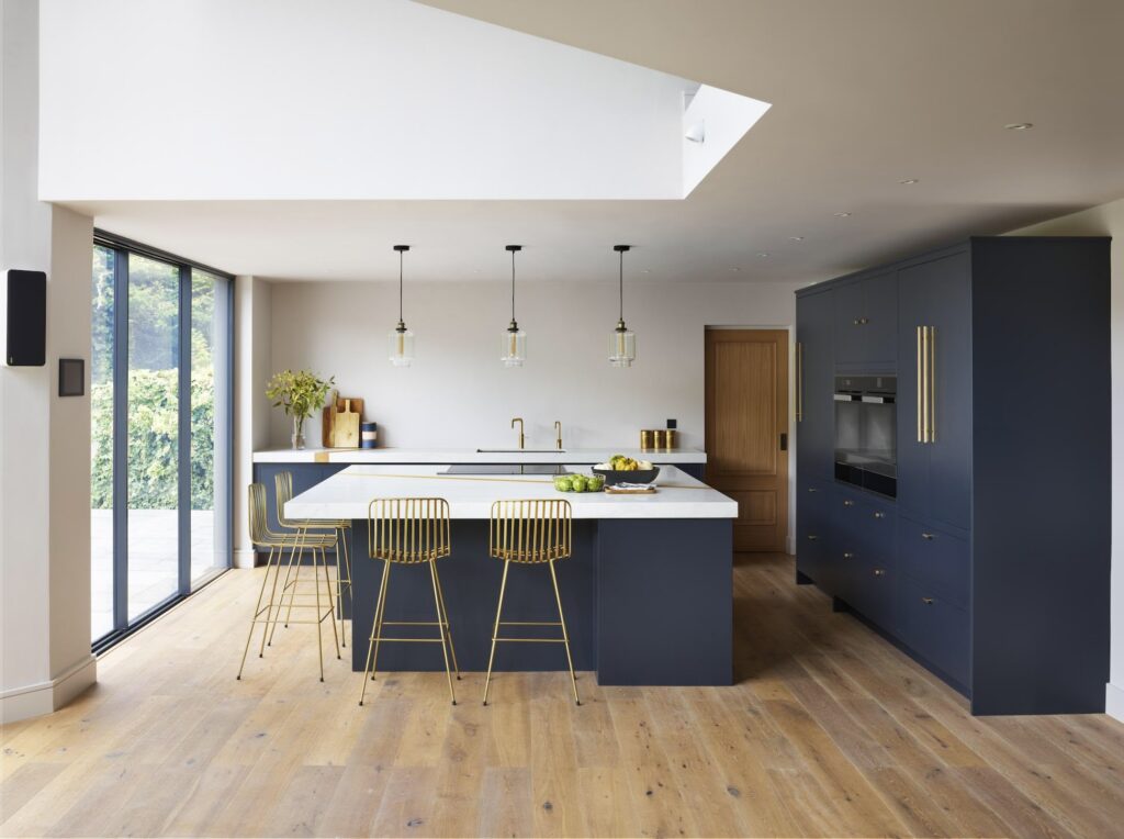 dark blue kitchen with gold island seating and wooden floor