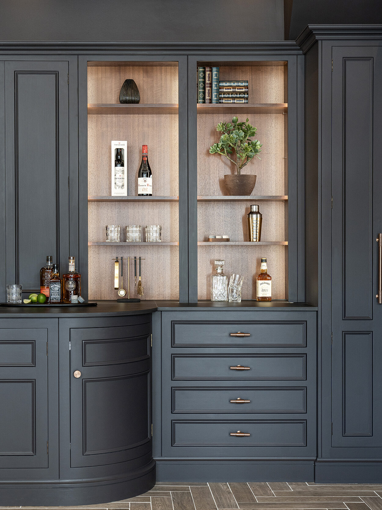 Dark kitchen with layered materials. Wood shelf backing and lighting with dark traditional style cabinetry