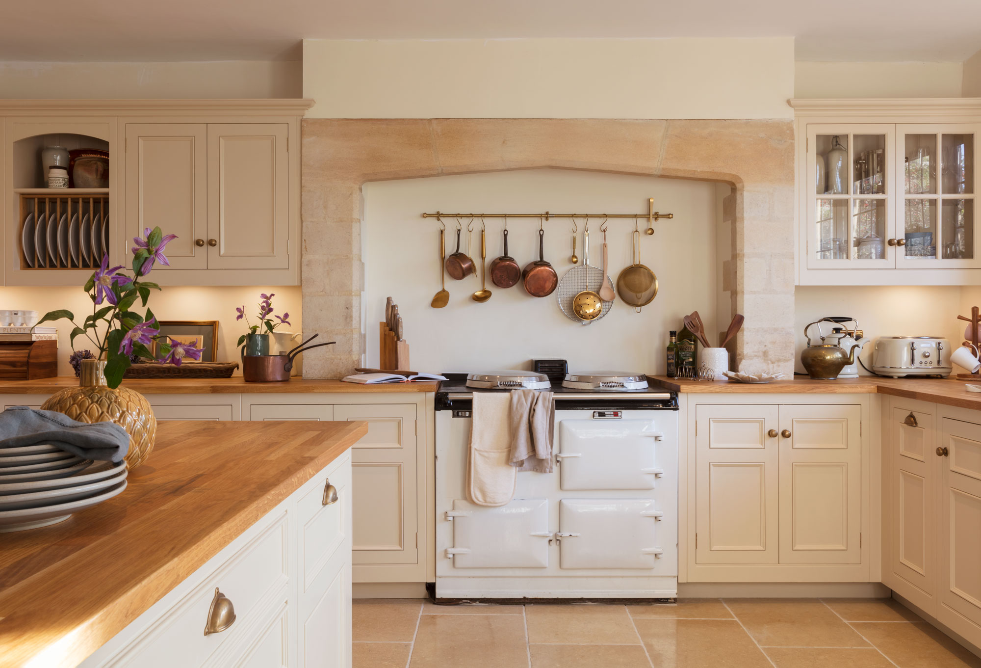 Country farmhouse kitchen with neutral cabinetry and statement AGA range cooker and island