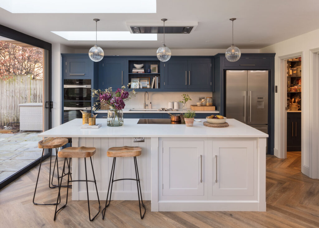blue and white kitchen with island and seating featuring wooden floor and walk in pantry