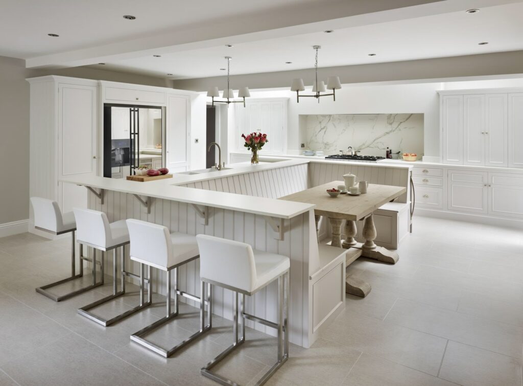 Neutral kitchen design with central banquette seating and breakfast bar seating for dining, preparation and open plan division