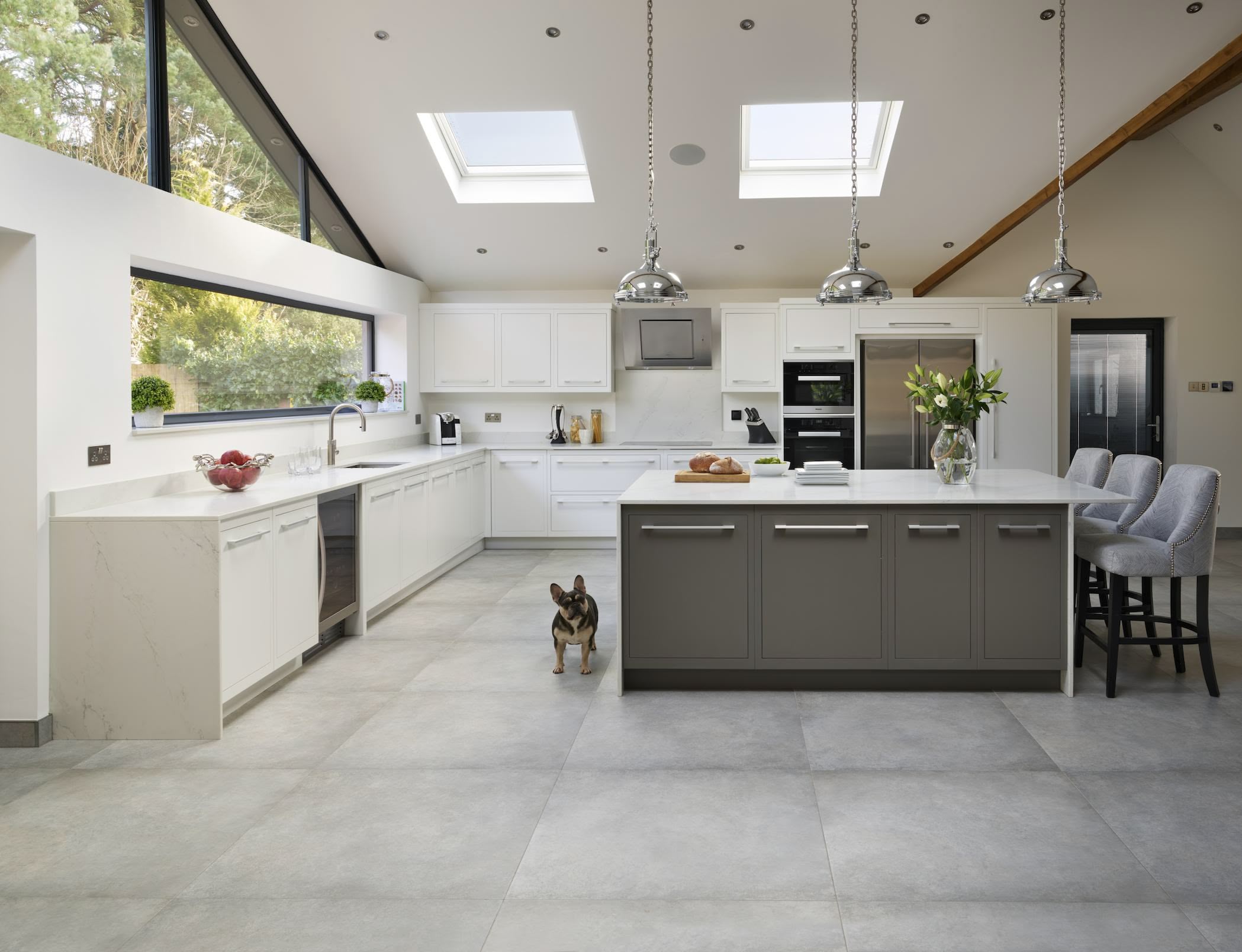 White minimalist kitchen design with contrasting island with seating, and stainless steel sleek handles