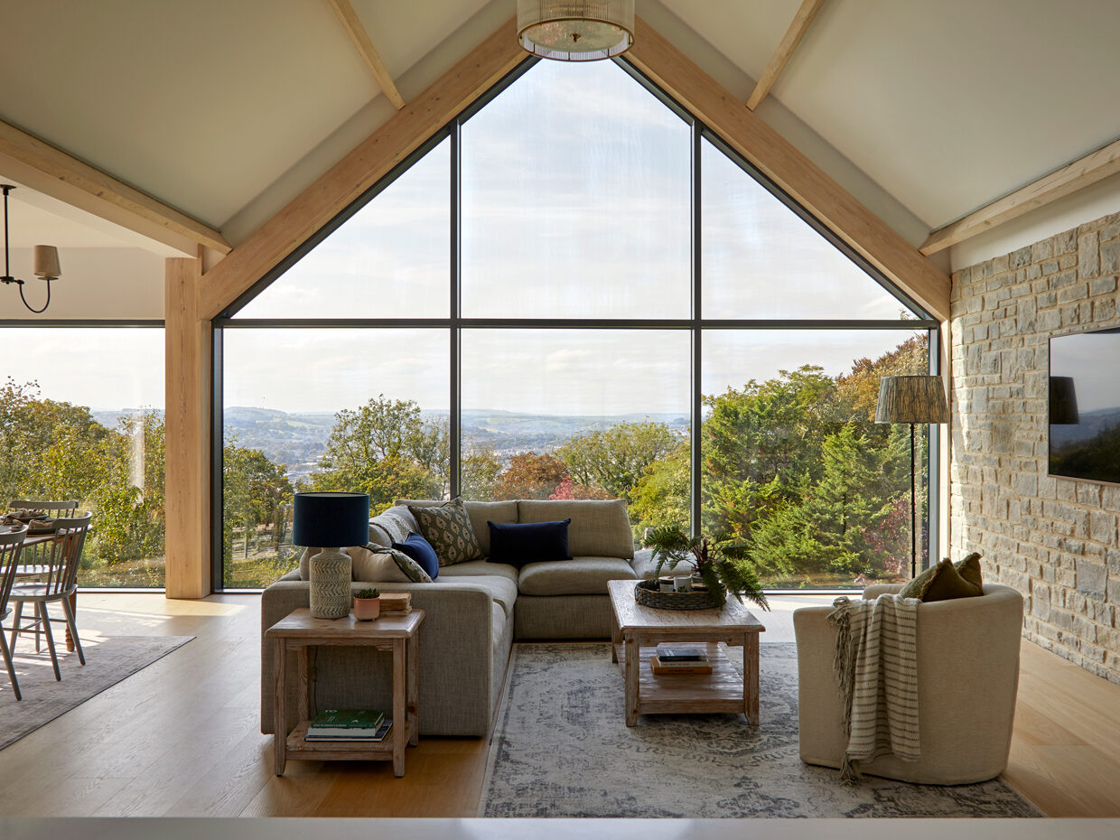 Open plan living room design with large gable end window and natural wood floor