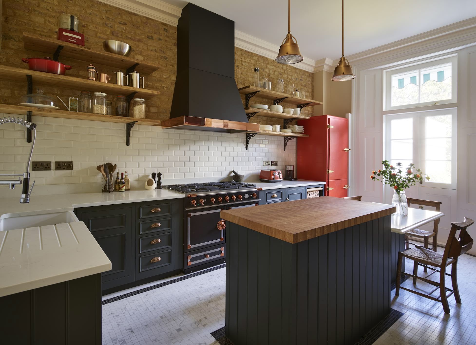 Industrial style kitchen with open shelving, blue cabinetry and butcher block island to match the kitchen as a preparation space