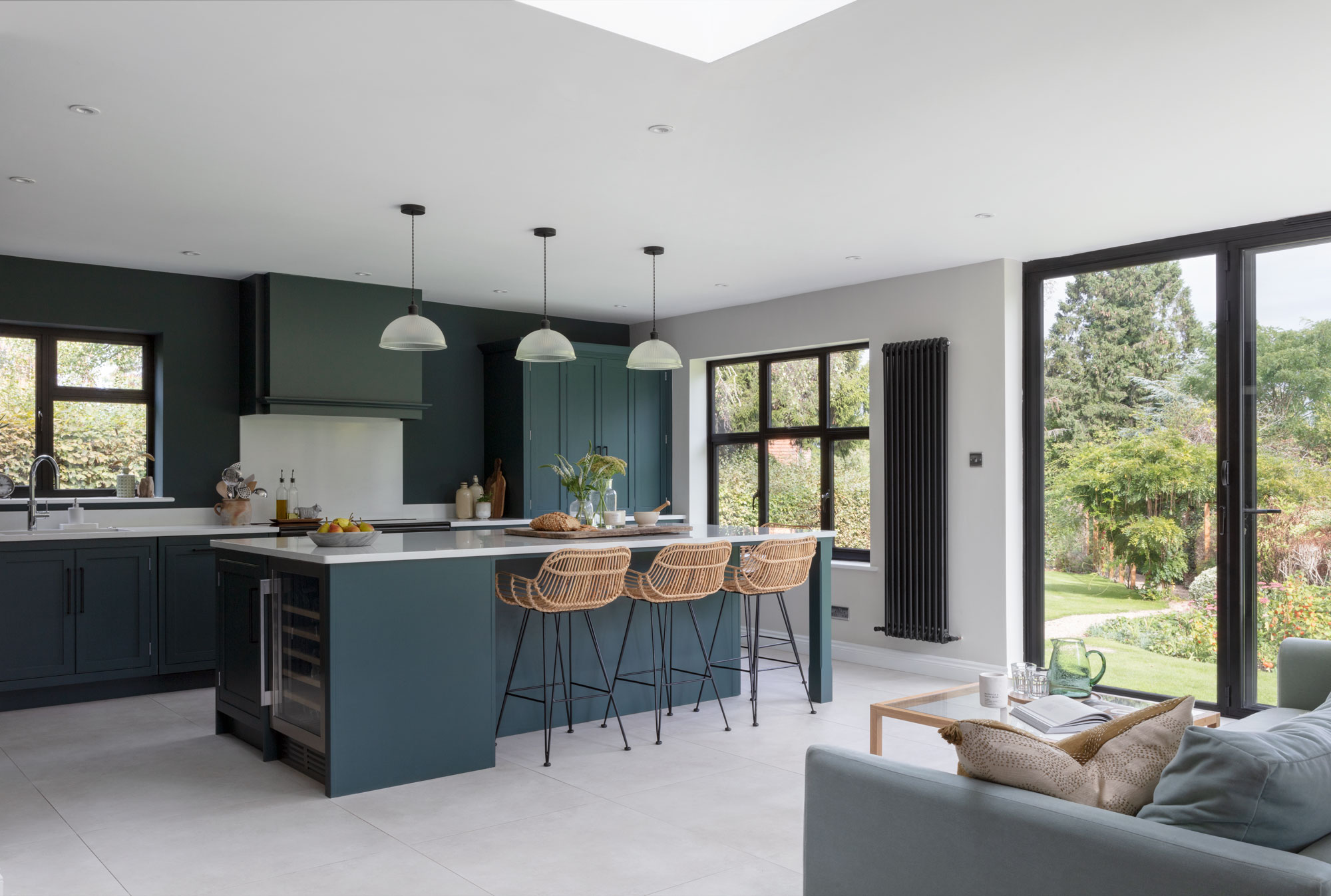 Dark open plan kitchen and living room with modern cabinetry and natural light