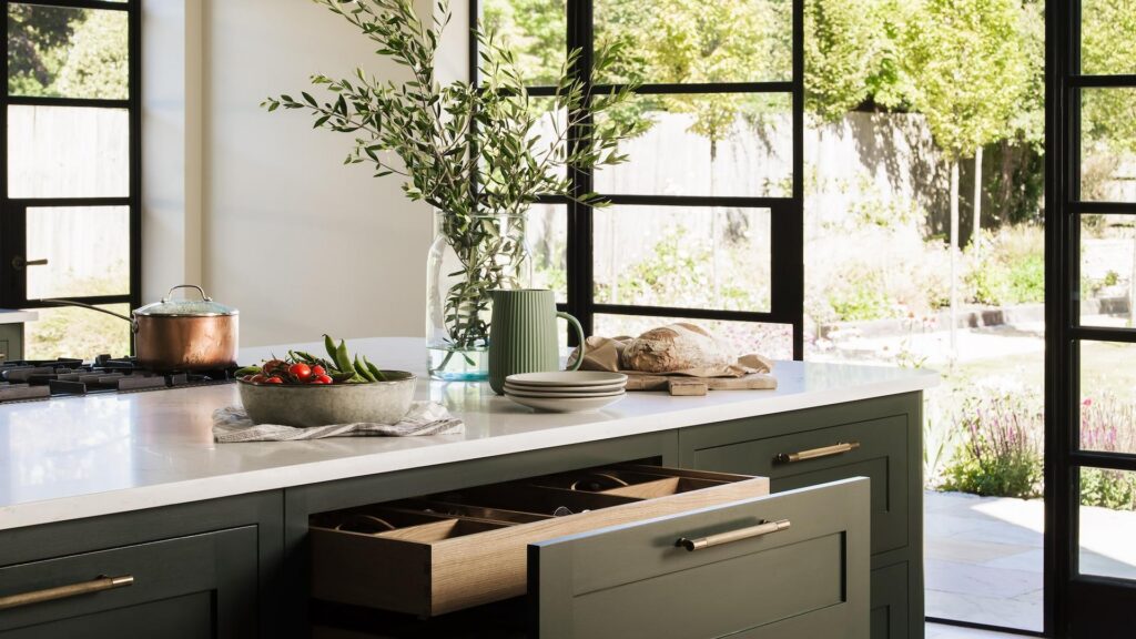 Dark green kitchen with oak internal drawers and black framed sliding doors