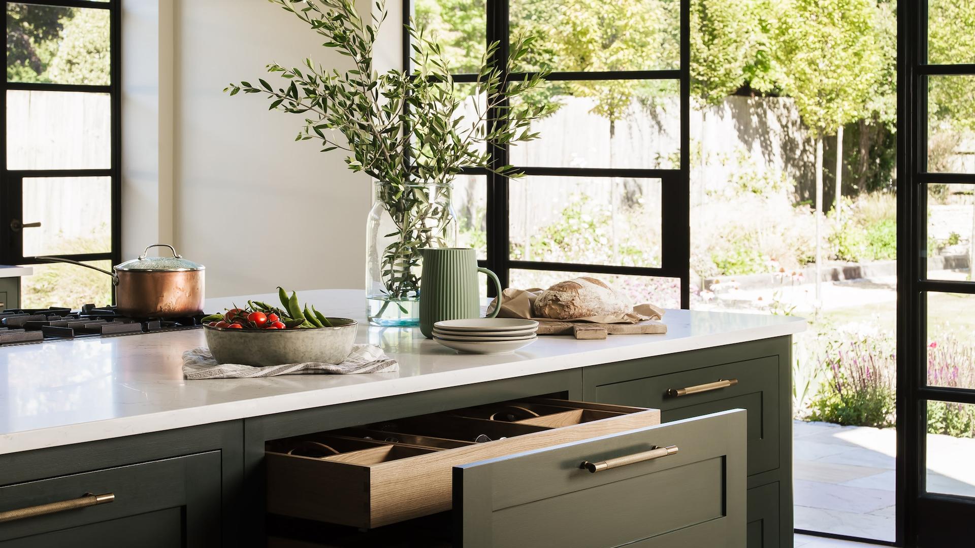 Dark green kitchen with oak internal drawers and black framed sliding doors