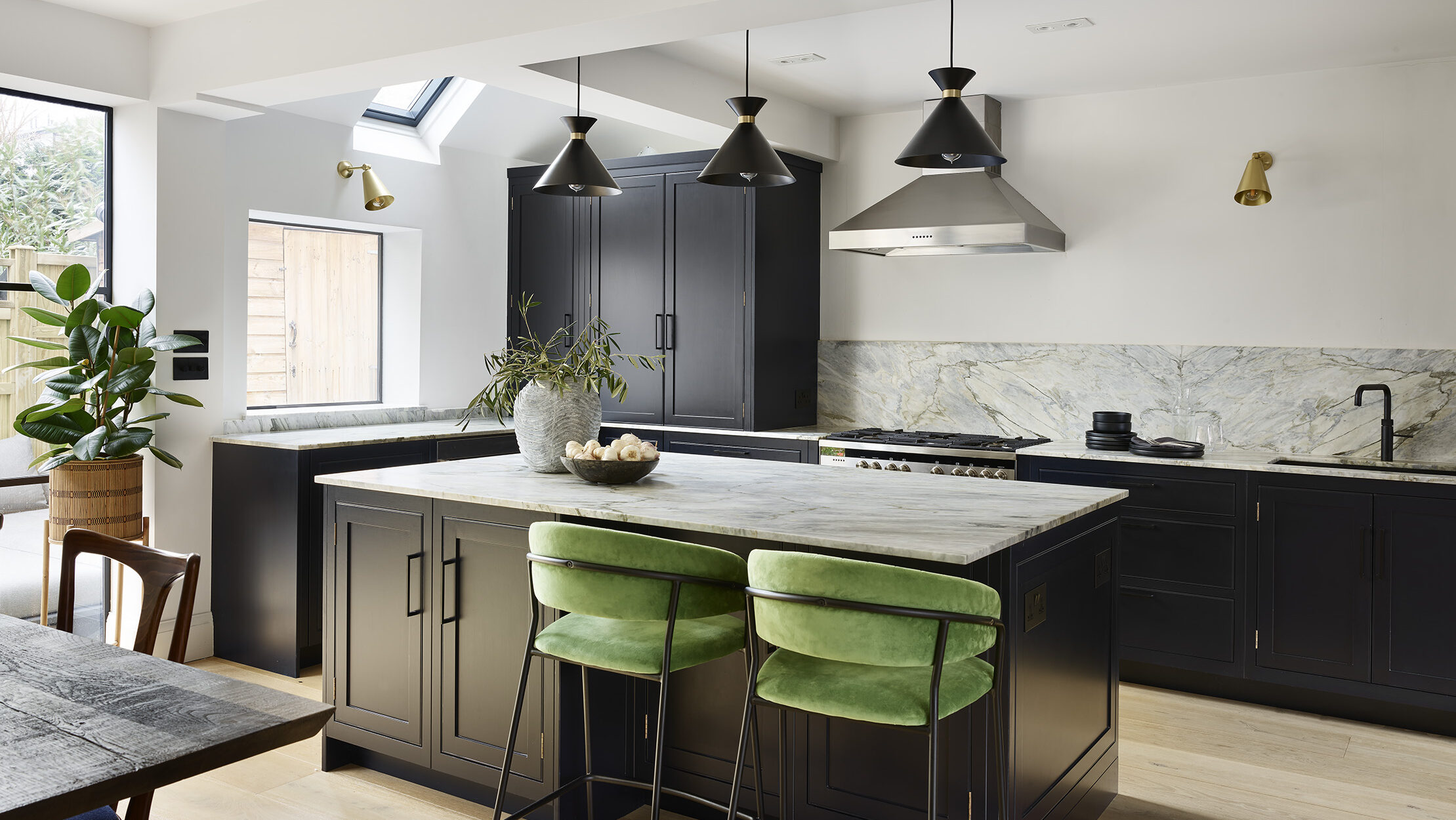 Navy blue L shaped kitchen with an island featuring green bar stools and pendant lighting
