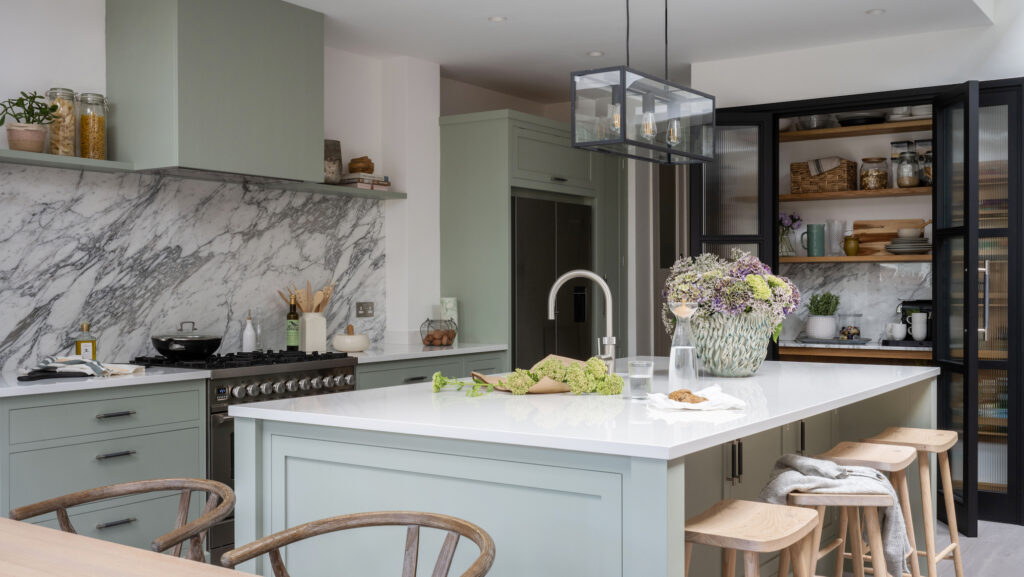 Sage green modern kitchen with a large kitchen island with natural wood accents and black accents