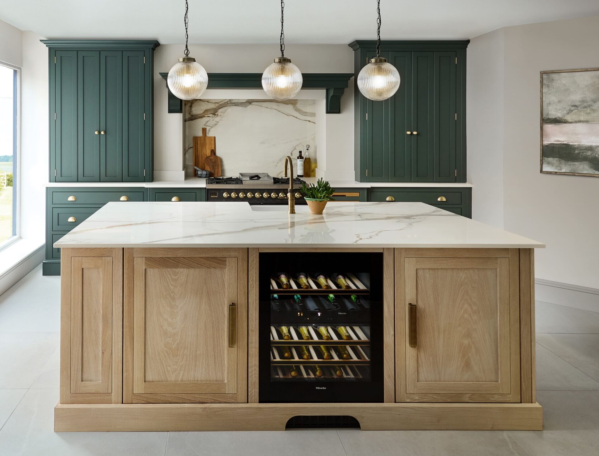 Modern shaker kitchen with dark green outer cabinetry and solid wood island with wine fridge and pendant lighting