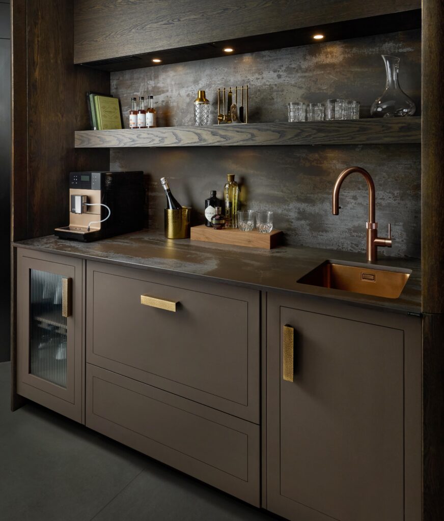 Black home bar with dark worktops and matching splashback featuring dark wooden shelving and sink