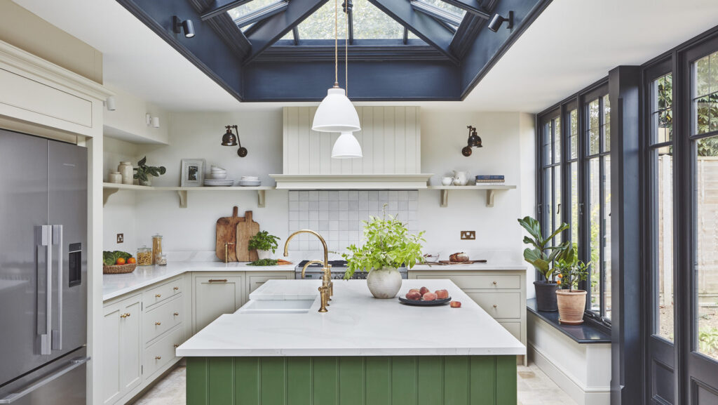 Orangery kitchen extension with green island and neutral cabinetry featuring black window frames and ceiling lantern
