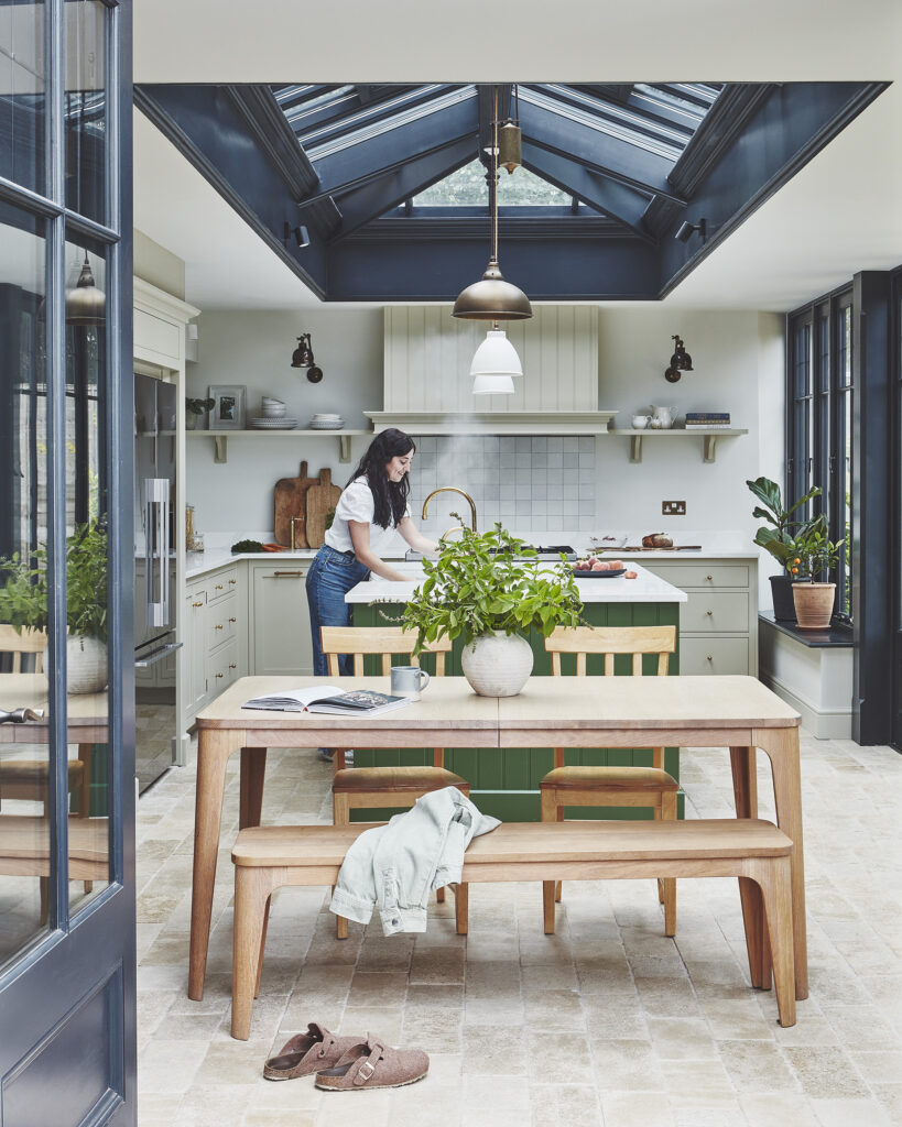 Orangery kitchen diner with large lantern roof, wooden table and vibrant green kitchen island