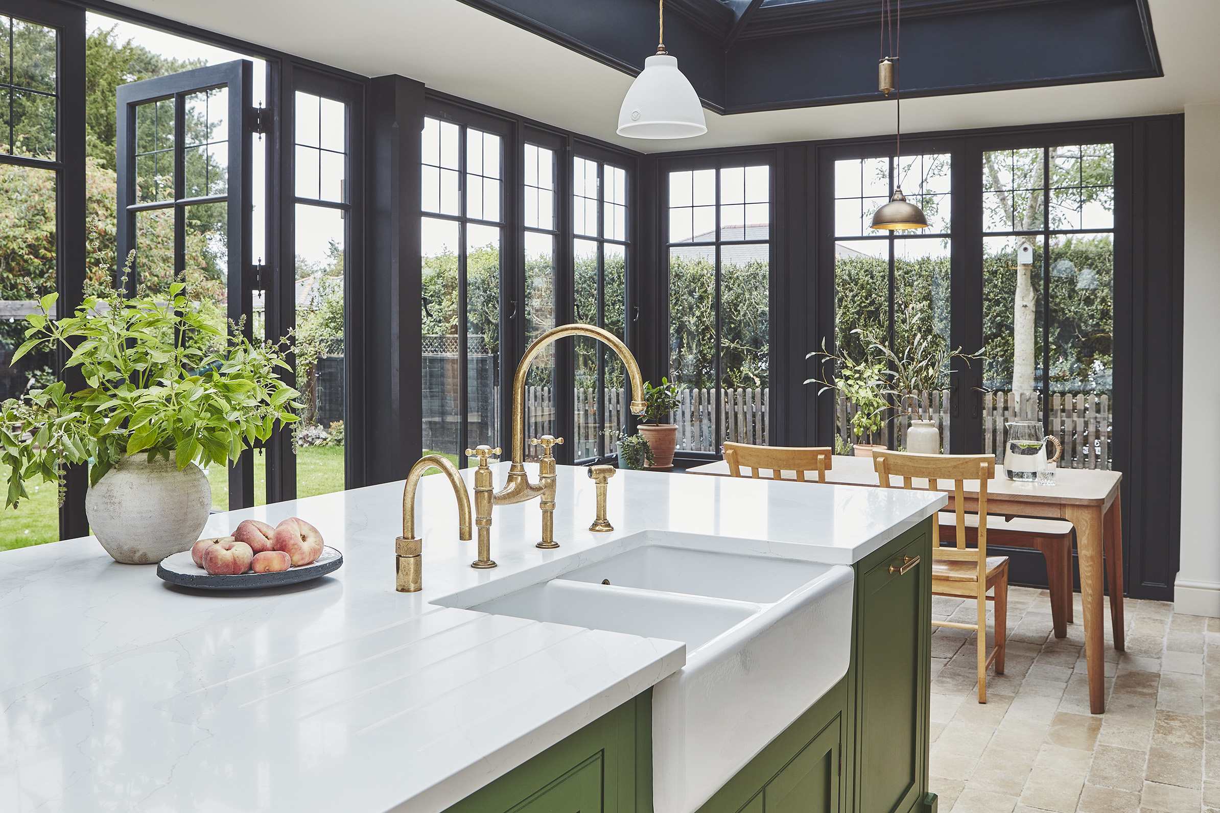 orangery kitchen extension with black frames and green island with dining table