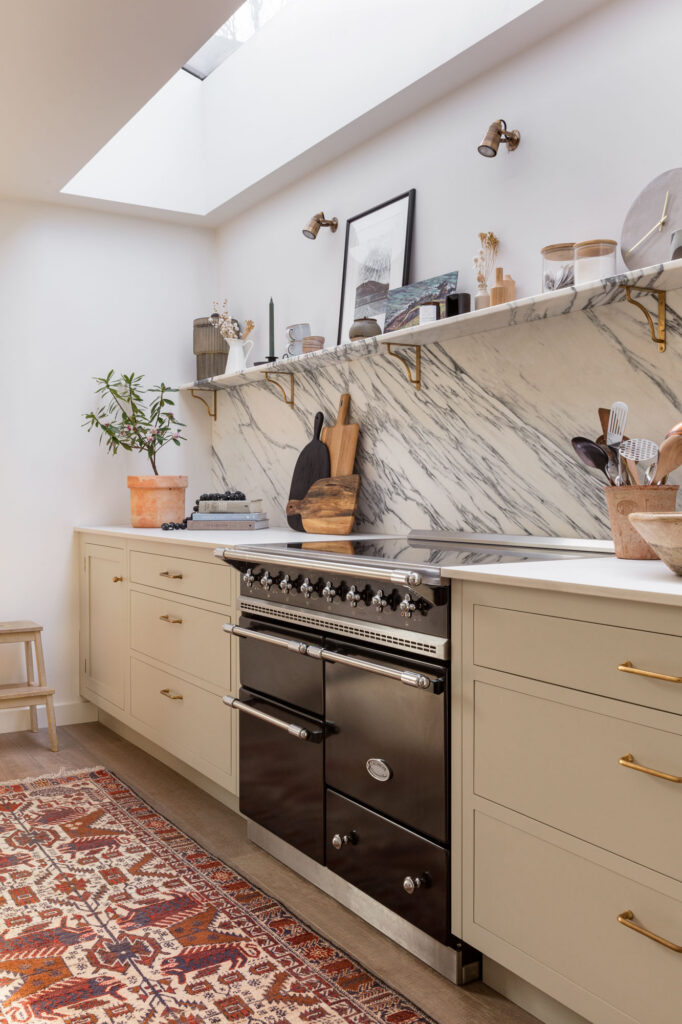 Modern neutral kitchen with skylight, rug and range cooker with quartz worktops and marble splashback