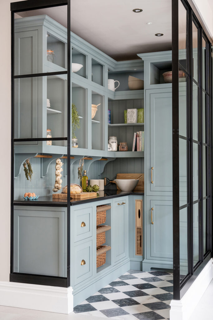 Light blue kitchen pantry with black and white tiled floor, open shelving and bespoke storage