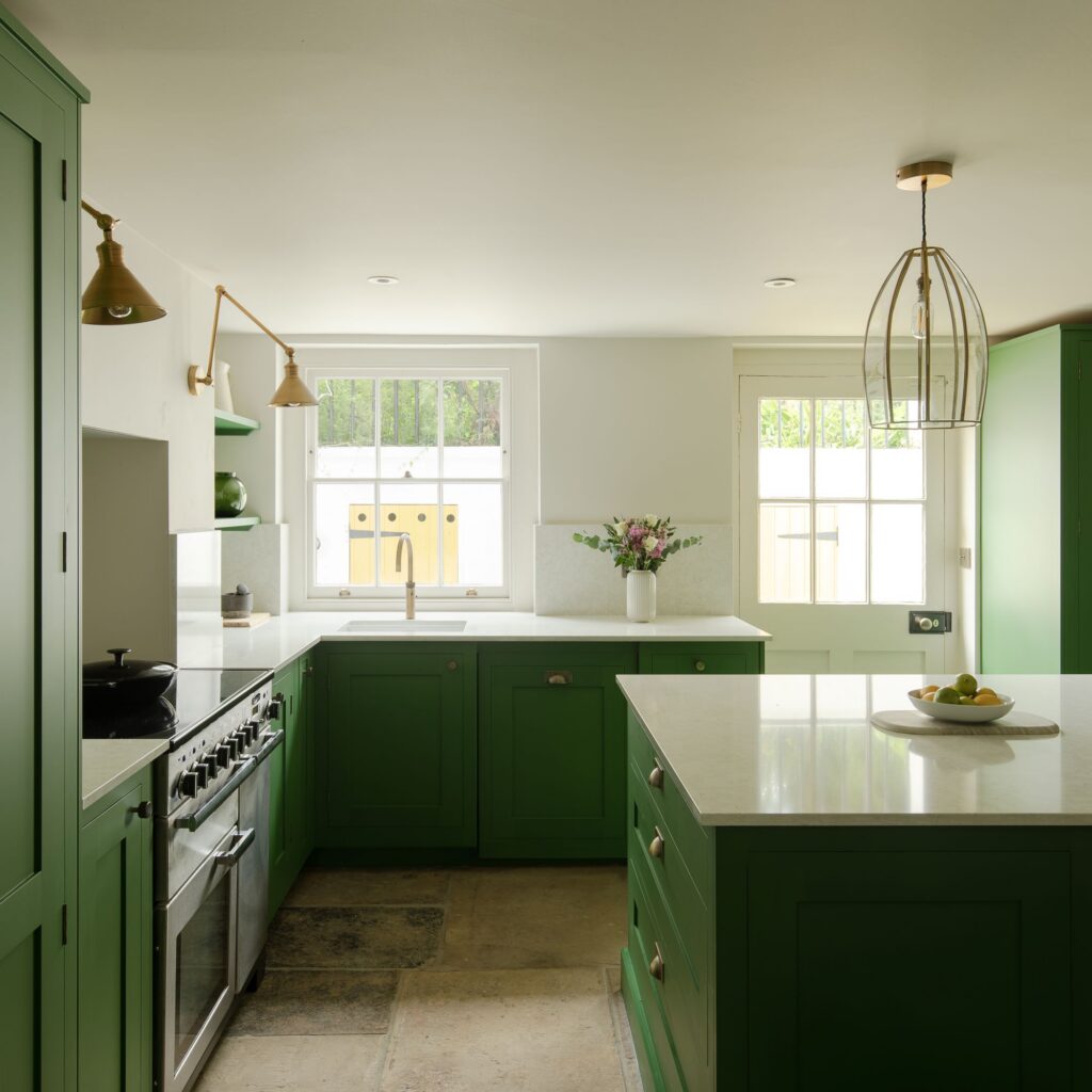Green and white Shaker kitchen design with layered lighting features